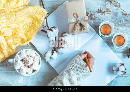 Frau Hand schreiben in Notepad, Tasse Kaffee, getrocknete Rose und Herbst Blatt. Herbst Winter schönen Hintergrund, gemütliche Home Konzept, kopieren. Stockfoto