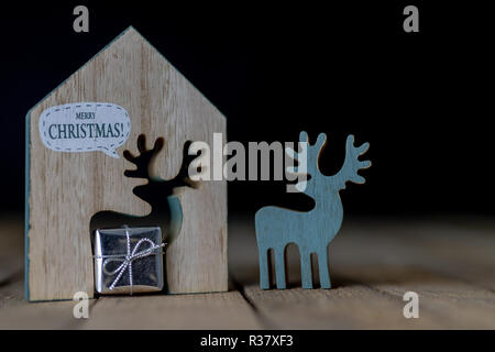 Weihnachtsschmuck auf dem Küchentisch. Holz- Weihnachten figuren vorbereitet für die Verzierung eines Baumes. Der dunkle Hintergrund. Stockfoto