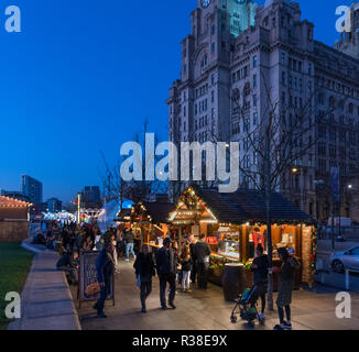 Weihnachtsmarkt Stände auf dem Weihnachtsmarkt Ice Festival Messegelände mit der Leber Gebäude hinter, Pier Head, Liverpool, England, UK Stockfoto