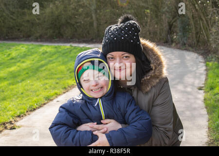 Mangels, Kinderbetreuung, Medizin und Personen Konzept - glückliche Mutter und Sohn mit Down-syndrom spielen in einem Park. Stockfoto