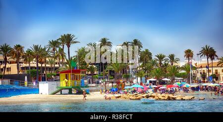 Santiago de la Ribera, Murcia, Spanien - 06. August 2018: Der Bademeister stationnext zu einem belebten Strand voller Urlauber, mit hohen Palmen in der Ba Stockfoto
