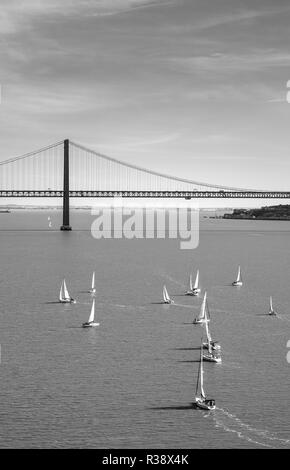 Segelboote auf dem Rio Tajo mit Ponte 25 de Abril, monochrom, Lissabon, Portugal Stockfoto