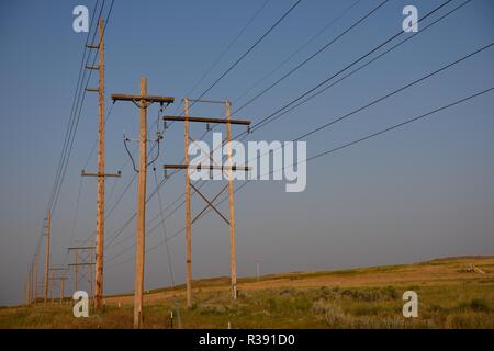 Reihen von elektrischen Übertragungsmasten und Hochspannungsfreileitungen bei Sonnenuntergang im ländlichen Wyoming, USA Stockfoto