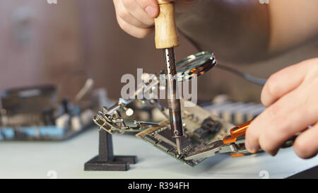 Die Reparatur der Hauptplatine. Service Techniker Mikrocontroller von Microchip. Fehlersuche. Mann unkenntlich. Stockfoto