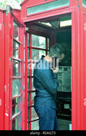 London, England, Vereinigtes Königreich. Mann mit einem traditionellen roten Telefonzelle entlang der Park Lane am Rande des Hyde Park in London's West End. Stockfoto