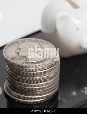 Stapel von Silber Quartalen Neben Mini piggy Bank, über Handy, Hochformat Stockfoto