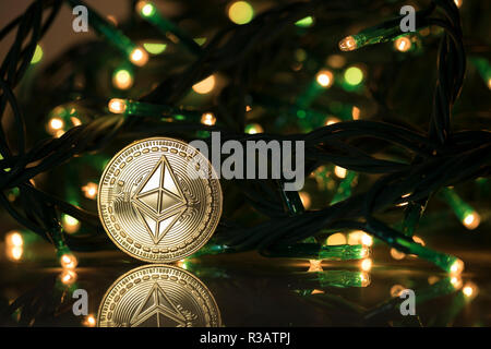 Des astraleums Classic cryptocurrency physischen Münze mit Weihnachtsbaumbeleuchtungen umgeben Stockfoto