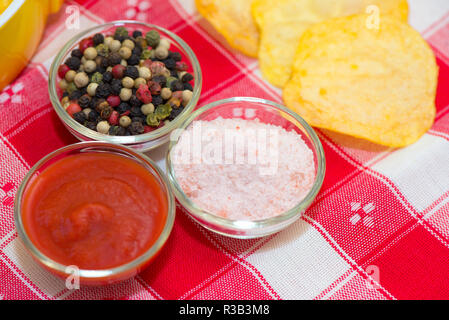 Ketchup, Salz Pfeffer in Schalen und Chips auf dem Tisch Tuch Stockfoto