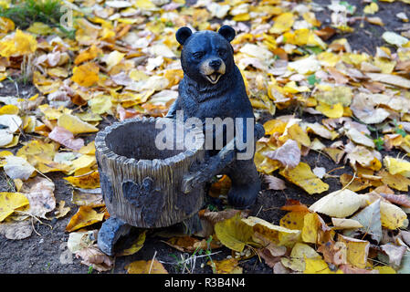 Holzfigur der Bär in den Wald park mit Futtertrog für Eichhörnchen und Vögel im Inneren. In der Schaufel sind Pinienkerne. Russland, Moskau Stockfoto