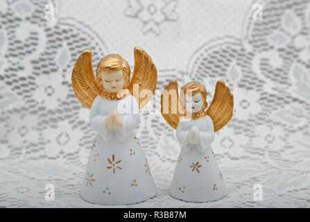 Zwei weiße kleine keramische Engel mit weißen spitzen Hintergrund Stockfoto