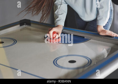 Die Hände der jungen Menschen holding Stürmer auf Air-Hockey-Tisch im Spiel Zimmer Stockfoto