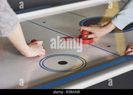 Die Hände der jungen Menschen holding Stürmer auf Air-Hockey-Tisch im Spiel Zimmer Stockfoto