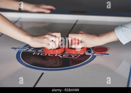 Die Hände der jungen Menschen holding Stürmer auf Air-Hockey-Tisch im Spiel Zimmer Stockfoto