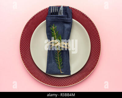 Weihnachten und Neujahr Platte, graue Platte auf rote Platte, mit Messer und Gabel und blau serviette mit Weihnachtsbaum auf rosa Hintergrund Stockfoto