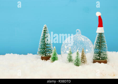 Bild von Weihnachtsbäumen in Glas Kugel über verschneite Holztisch Stockfoto