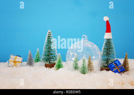 Bild von Weihnachtsbäumen in Glas Kugel über verschneite Holztisch Stockfoto