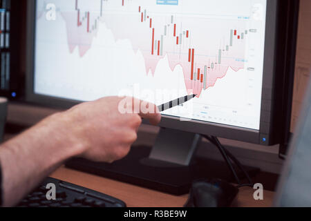 Die Analyse der Daten. Nahaufnahme der junge Unternehmer, der auf die Daten in der Tabelle mit Pen präsentiert, während in der kreativen Arbeiten im Büro Stockfoto