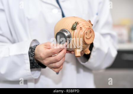Arzt Holding piggy Bank schließen. Krankenversicherung und Gesundheitsversorgung geld Konzept. Stockfoto