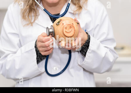 Financial Check up. Arzt holding Sparschwein mit Stethoskop Stockfoto