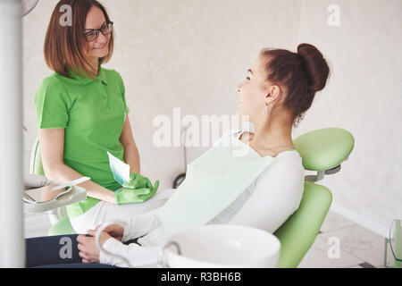 Weibliche Zahnarzt in der Zahnarztpraxis im Gespräch mit der Patientin und die Vorbereitung der Behandlung Stockfoto