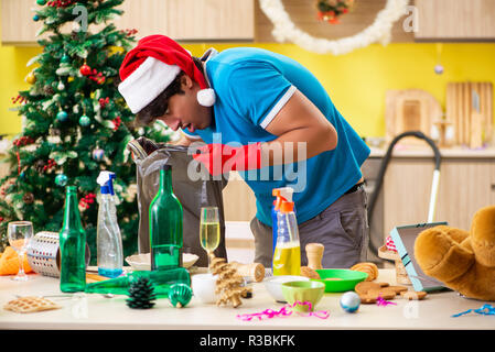 Junger Mann Reinigung Küche nach Weihnachtsfeier Stockfoto