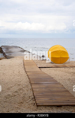 Strand mit Sonnenschirm verlassen Nach dem Regen Stockfoto