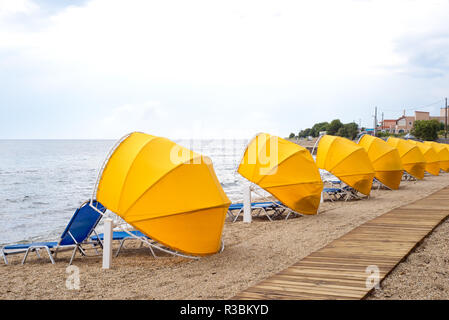 Holzsteg, Sonnenschirme und Sonnenliegen am Strand Stockfoto