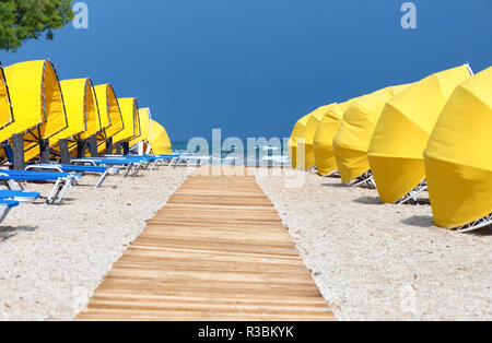 Holzsteg, Sonnenschirme und Sonnenliegen am Strand Stockfoto