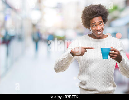 Afro-amerikanischer Mann trinken Tasse Kaffee über isolierte Hintergrund sehr glücklich zeigte mit Hand und Finger Stockfoto