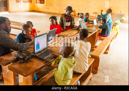 Bafoussam Kamerun - 06. August 2018: Junge afrikanische Lehrer die Kinder in der Schule lernen-Technologie mit dem Computer verbunden Stockfoto