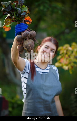 Foto der jungen Frau mit rote Beete im Garten, verschwommenen Hintergrund Stockfoto