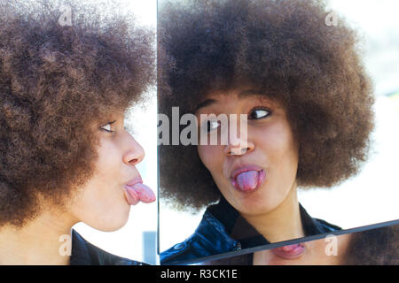 Mädchen mit afrofrisur das dehnen ihre Zunge Stockfoto