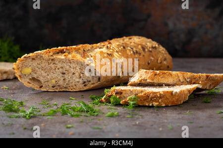 Brot mit verschiedenen Samen (Kürbis, Mohn, Flachs, Sonnenblumen-, Sesam, Hirse) dekoriert mit gehacktem grünen Dill Stockfoto