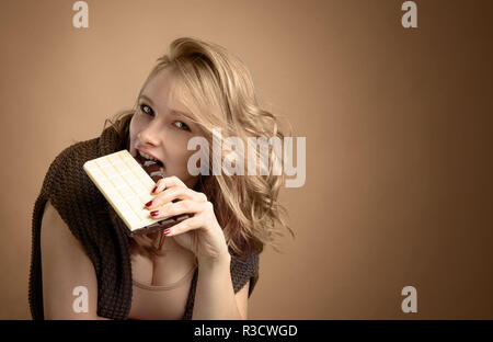 Glückliche junge schöne Frau Schokolade essen. Junge Blondine mit natürlichen Make-up Spaß und Schokolade essen. Stockfoto