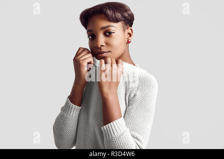 Porträt der jungen schönen Hipster schwarz Mädchen mit kurzen Haaren in weißen Pullover auf weißem Hintergrund. Studio schießen. Stockfoto