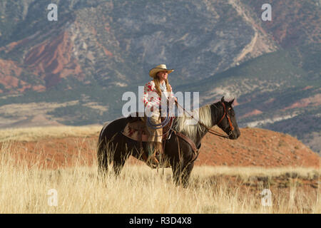 Usa, Wyoming, Shell, das Versteck Ranch, Cowgirl zu Pferd in den Hügeln (MR, PR) Stockfoto