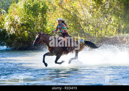 Usa, Wyoming, Shell, das Versteck Ranch, cowgirl Reiten über den Fluss (MR, PR) Stockfoto