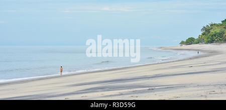 Zwei Menschen in der Ferne Spaziergang entlang getrennt gesehen, auf einer ansonsten leeren Strand bei Ebbe. Stockfoto