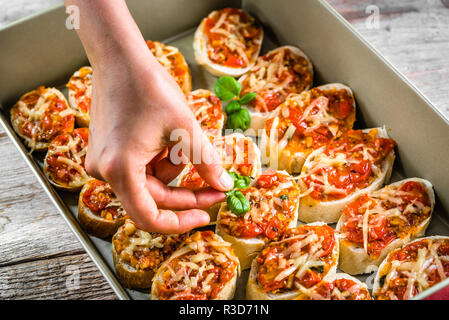 Küchenchef bereitet italienische Bruschetta mit Tomaten, Basilikum und Käse garnieren Essen, kochen Hausgemachte Vorspeisen für die Partei Stockfoto