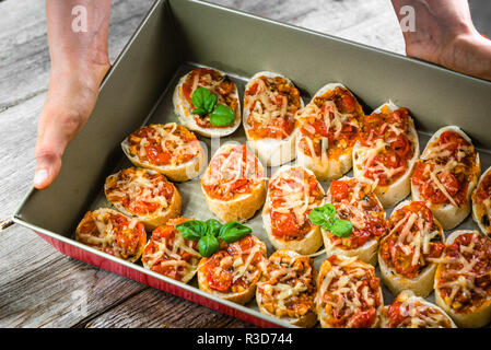 Koch, Essen - Italienisch Bruschetta mit Tomaten, Basilikum und Käse, kochen Hausgemachte Vorspeisen für die Partei Stockfoto