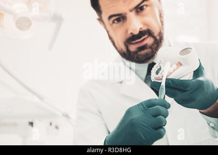 Richtige Zahnreinigung. In der Nähe von schweren Arzt mit Zahnbürste und zahnmedizinische Modell der vor Dir steht, während das Erklären der richtigen Zähne Brus Stockfoto