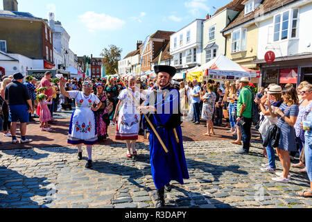 Faversham Hop Festival, Parade. Balaton ungarische Tänzer unter der Leitung von Mann in blauem Gewand, durch überfüllte Straße marschieren mit Zuschauer. Stockfoto