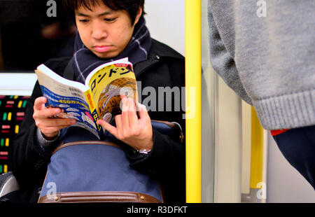 Junge Japaner Lesen eines Hentai Graphic Novel auf einer U-Bahn, London, England, UK. Stockfoto