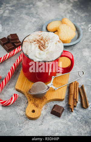 Weihnachten rot emaillierten Becher mit heißer Schokolade und Sahne, Zimtstangen, Anis Sterne und Herzhaftes shortbread Sugar Cookies und Zuckerstangen auf Stockfoto