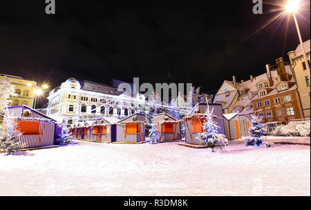 Livu Platz mit Weihnachtsmarkt im Herzen der Altstadt von Riga, Lettland in der Nacht mit dem russischen Theater Drama in einem Hintergrund Stockfoto