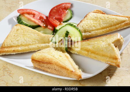 Ein Schuß von drei Dreieck Sandwiches mit Tomaten und Gurke auf der Seite. Stockfoto