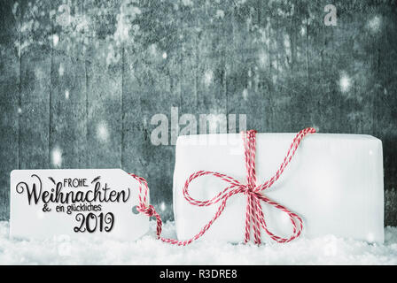 Etikett mit Deutschen Kalligraphie Frohe Weihnachten und ein Glueckliches 2019 bedeutet, frohe Weihnachten und einen guten Rutsch ins Jahr 2019. Eine weiße Geschenk mit roter Ribbn. Grung Stockfoto