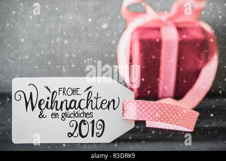 Etikett mit Deutschen Kalligraphie Frohe Weihnachten und ein Glueckliches 2019 bedeutet, frohe Weihnachten und einen guten Rutsch ins Jahr 2019. Ein rosa Geschenk mit Ribbn. Zement Bac Stockfoto