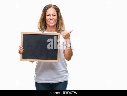 Mittleres Alter spanischer Frau mit blackboard über isolierte Hintergrund mit Lächeln tun ok Zeichen glücklich, Daumen hoch, mit den Fingern, ausgezeichnete Zeichen Stockfoto