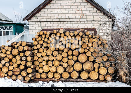 Stapel geschnittenen Holz in der Nähe von House gestapelt. Brennholz Holz Material für Heizung im Winter an der alten ländlichen Gebäude Stapel vorbereitet. Stockfoto